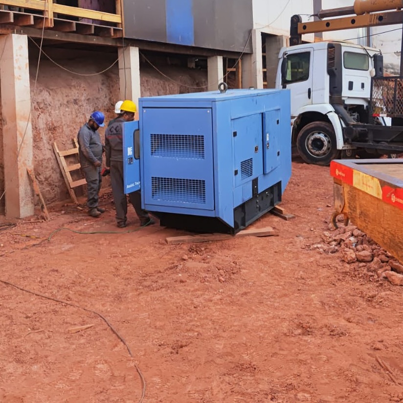 Gerador azul posicionado em obra com equipe técnica