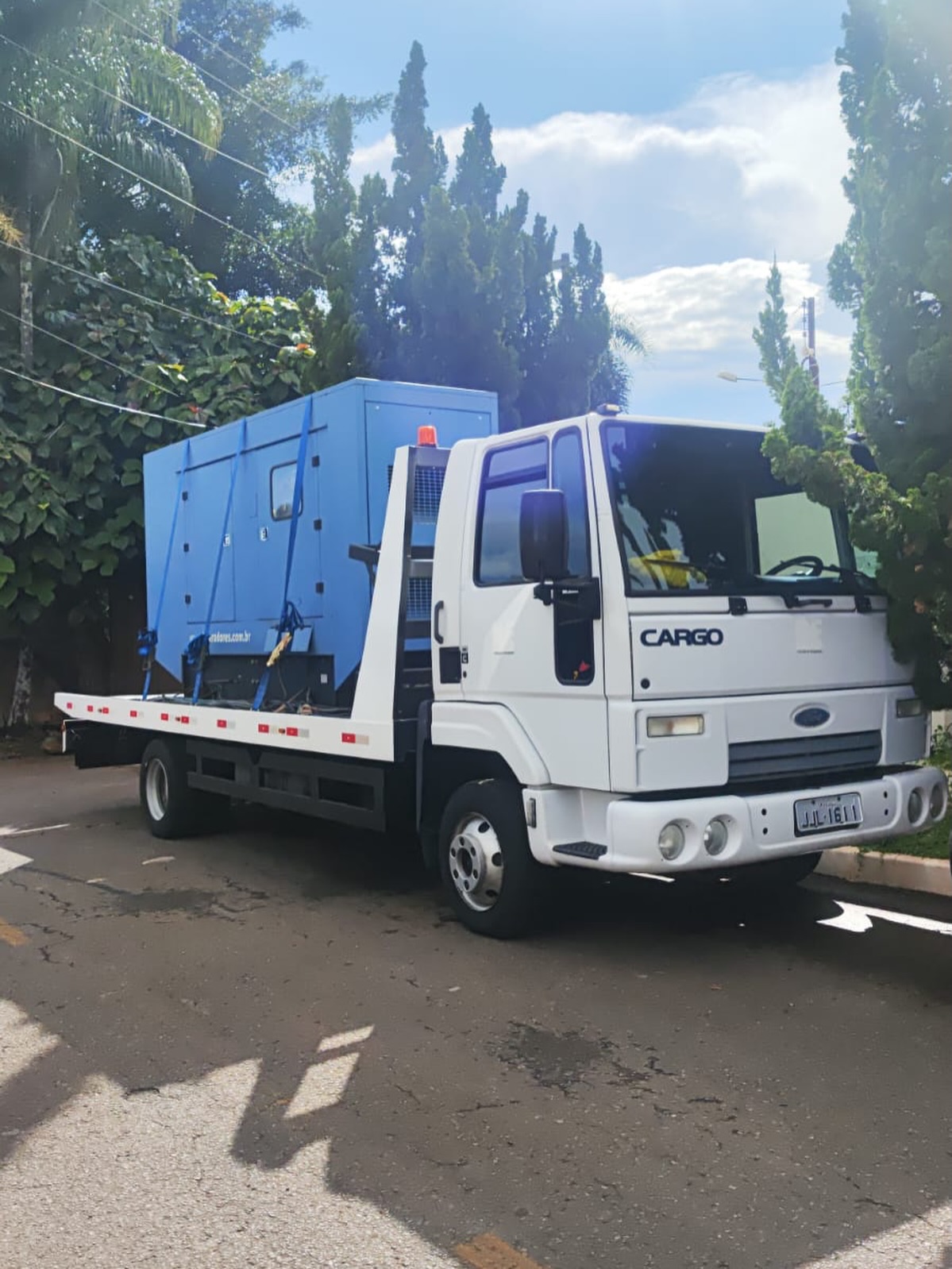 Gerador azul carregado em caminhão prancha branco
